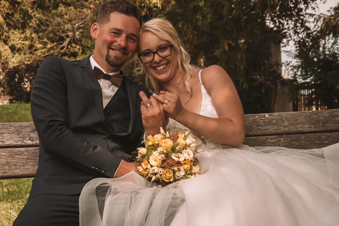 Mladoporočenca v Domžalah, Kamniku ali Moravčah; naravna bližina na podeželju, topli toni in pristna gesta v umirjeni, dokumentarni fotografiji.